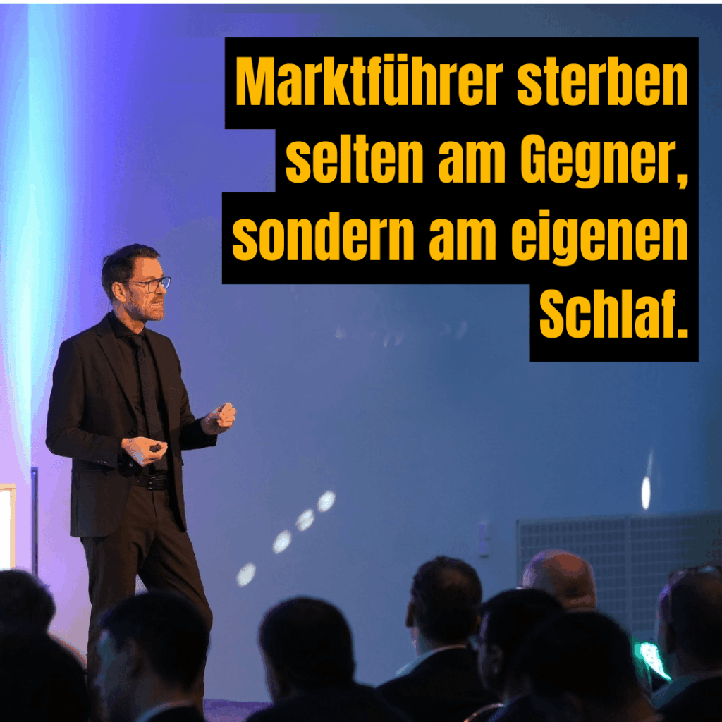 Peter Kreuz beim Vortrag – im Hintergrund das Zitat: „Marktführer sterben selten am Gegner, sondern am eigenen Schlaf."