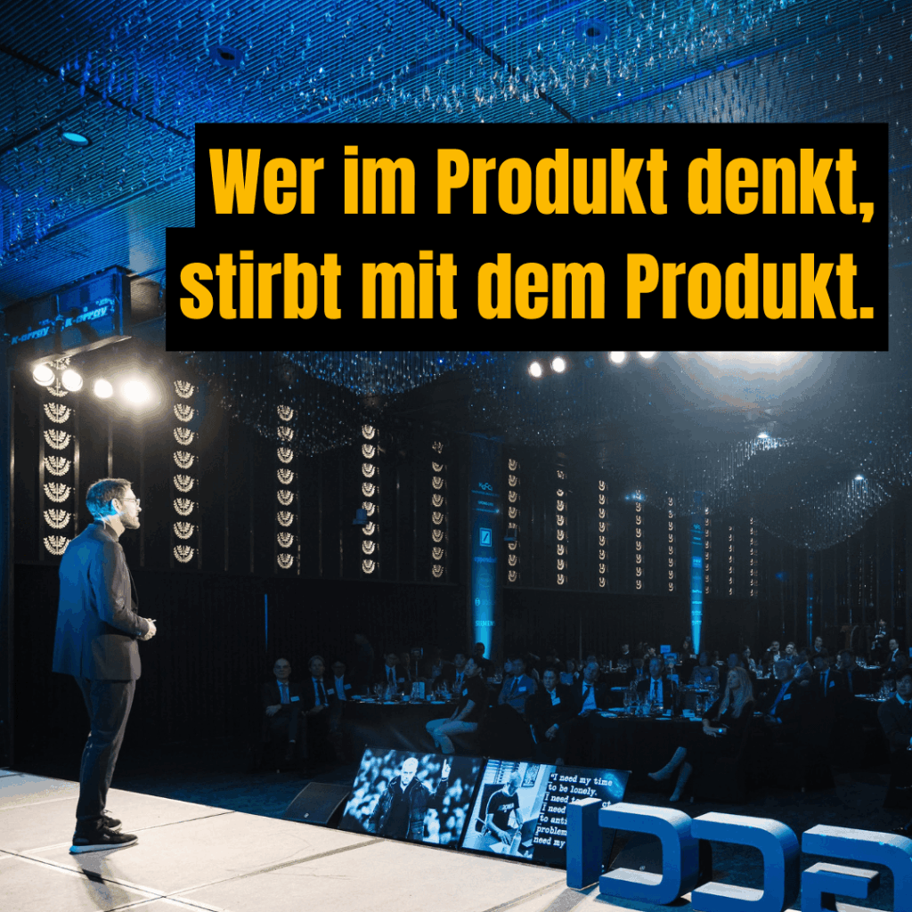 Peter Kreuz auf der Bühne während eines Vortrags mit der Aussage „Wer im Produkt denkt, stirbt mit dem Produkt.“